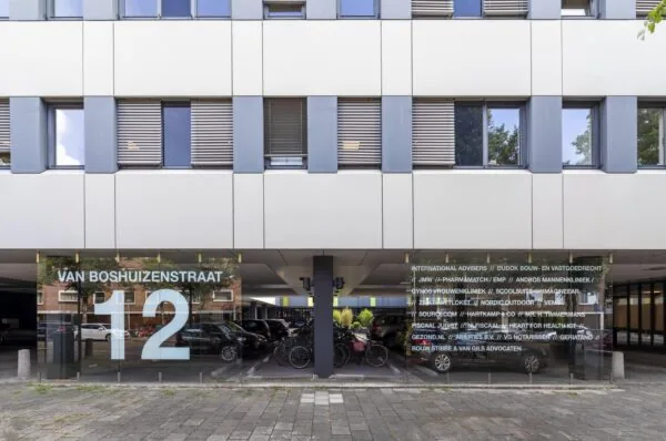 Entree van een kantoorgebouw aan de Van Boshuizenstraat 12 met namen van bedrijven op de glazen gevel.